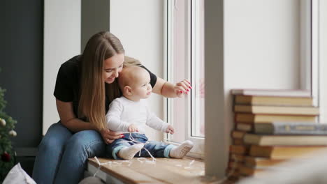 madre con bebé sentada en la ventana y jugando