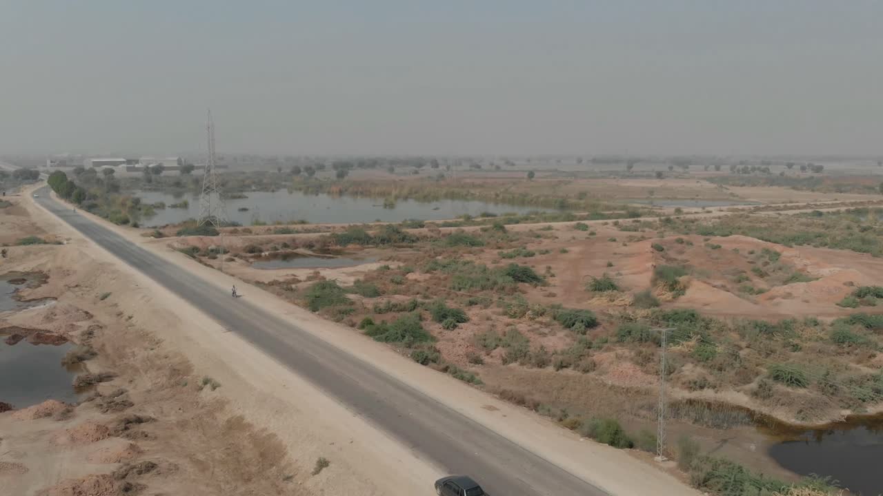 una toma inclinada hacia abajo de un hermoso pueblo rural camino asfaltado camino al lado de los árboles del campo de pastizales hasta el horizonte
