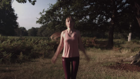 On-a-sunny-day,-a-woman-is-seen-doing-a-Jumping-Jack-in-the-park's-outdoor