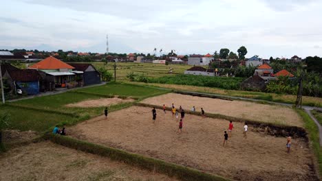 los niños juegan al fútbol en el campo rural, indonesia, el tiempo aéreo del partido de pelota de los niños cae en el campo de arroz de bali, el campo en el área local