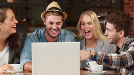 amigos hipsters sonrientes riéndose de una computadora portátil