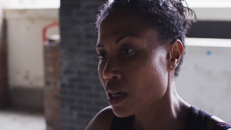 retrato de una mujer afroamericana de pie y descansando después de hacer ejercicio en un edificio urbano vacío