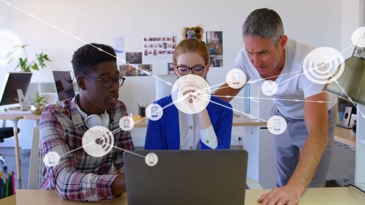 Team leaning over laptop, left colleague speaking and starting network overlay showing tech links