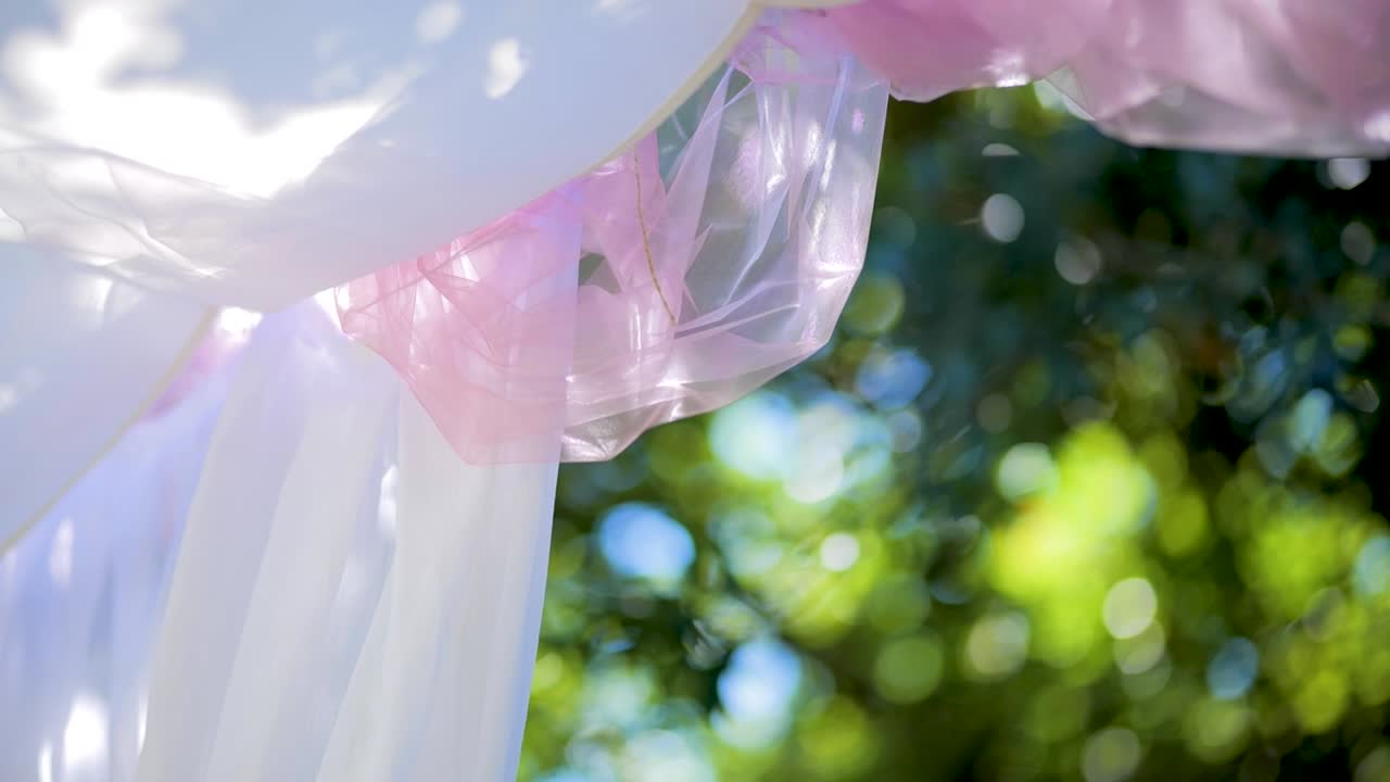Outdoor Pergola Decoration with Pink Details, Leaves in the Wind, and Green Trees for Wedding or Christening Party