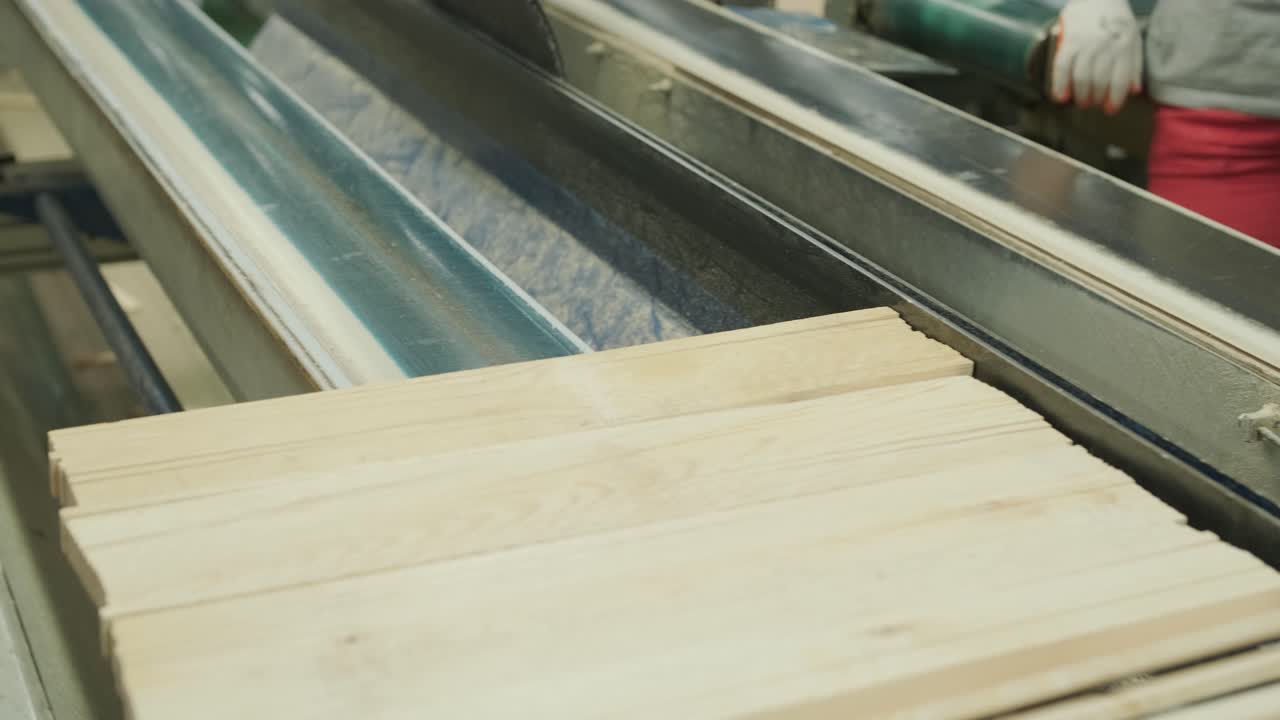 Operaio che posiziona assi di legno su un nastro trasportatore in fabbrica