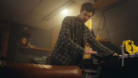 Confident-guy-in-a-checkered-shirt-puts-tools-in-his-box-after-repairing-a-motorcycle-in-a-workshop