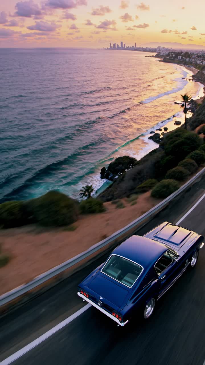 Aerial video captures a classic car driving along a coastal road at sunset, showcasing scenic ocean