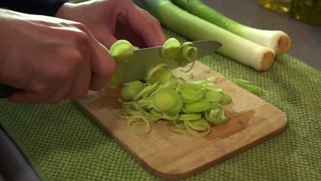 cu male chef preparing fresh leeks, chopping them with a sharp knife to create a dish