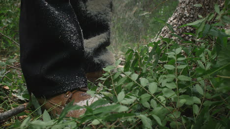 saw dust landing on mans feet in cinematic slow motion during tree felling