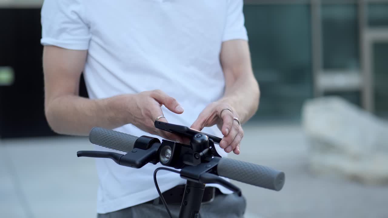 젊은 사업가 가 드폰 으로 전자 스쿠터 를 활성화 하는 장면