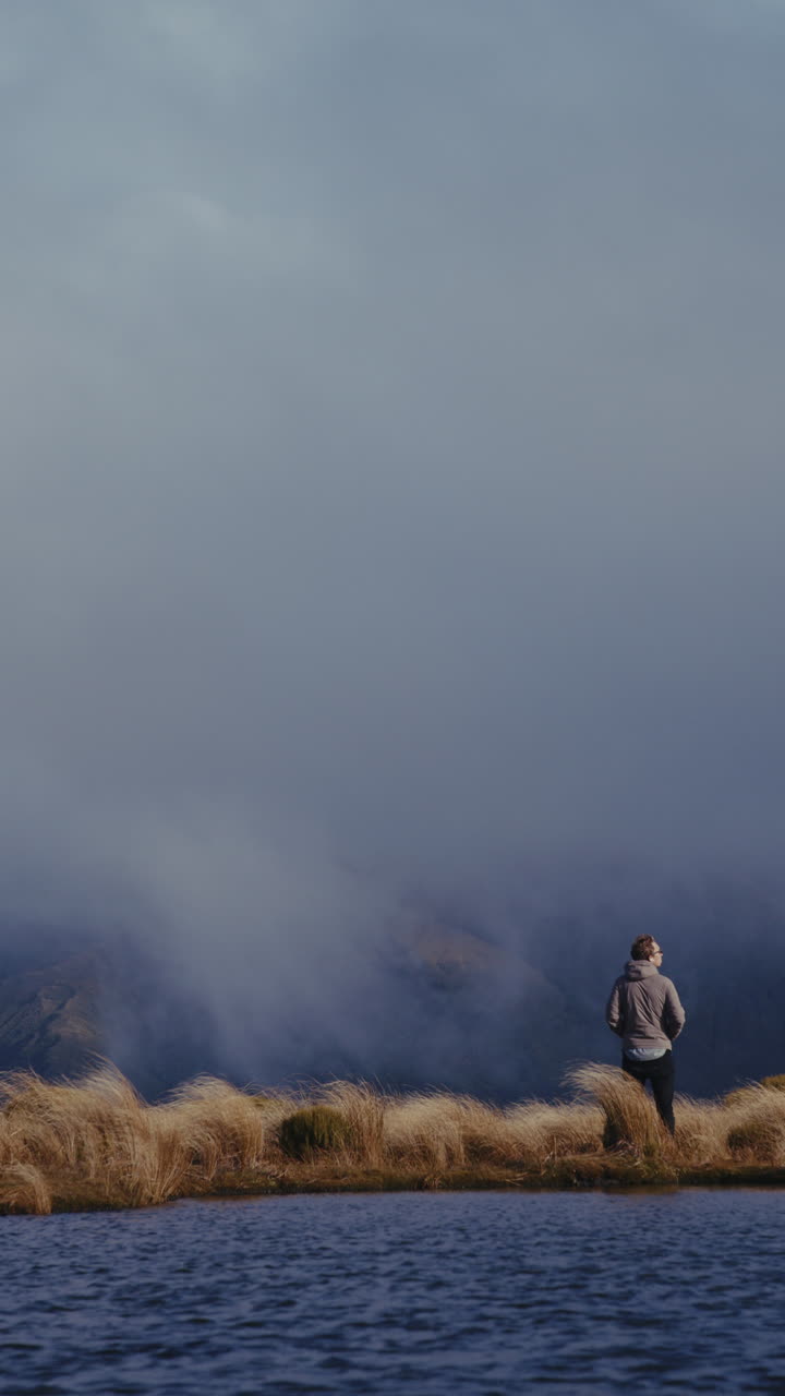 Man standing on a mountaintop overlooking a lake shrouded in mist
