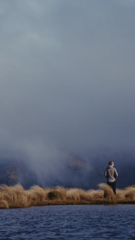man standing on a mountaintop overlooking a lake shrouded in mist