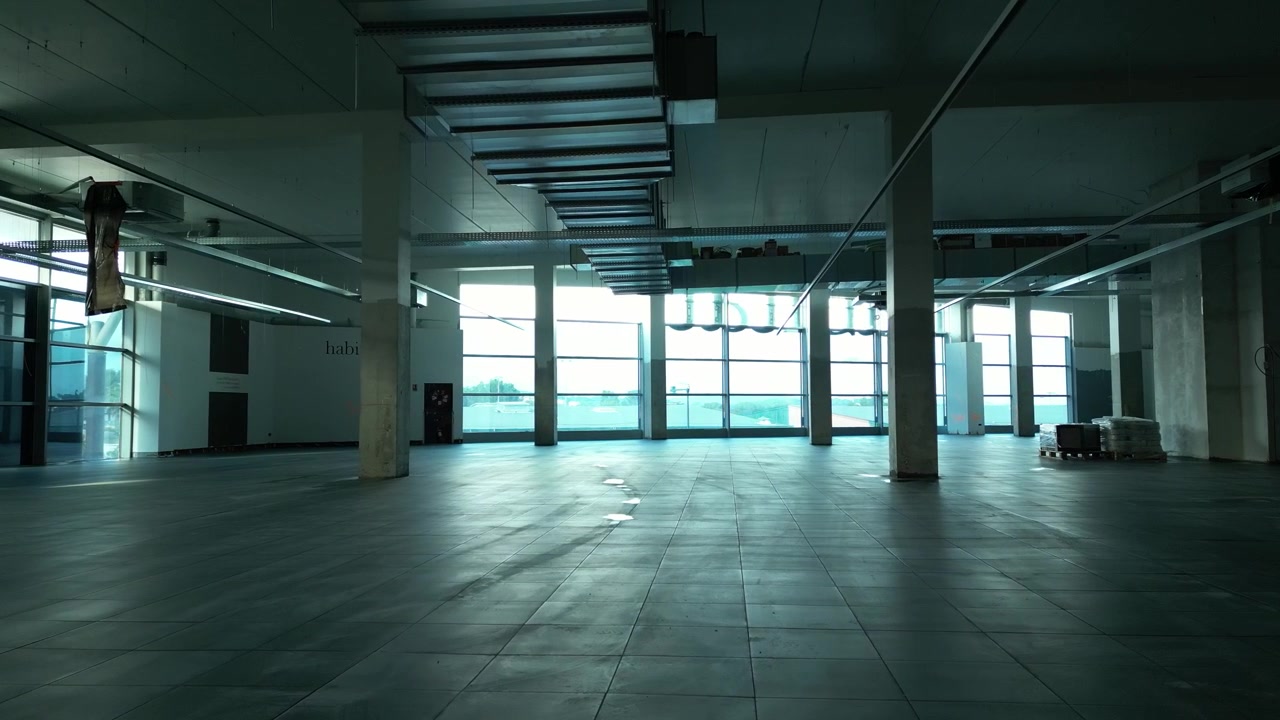 Espacio industrial vacío con grandes ventanales y estructura expuesta con luz natural tenue.