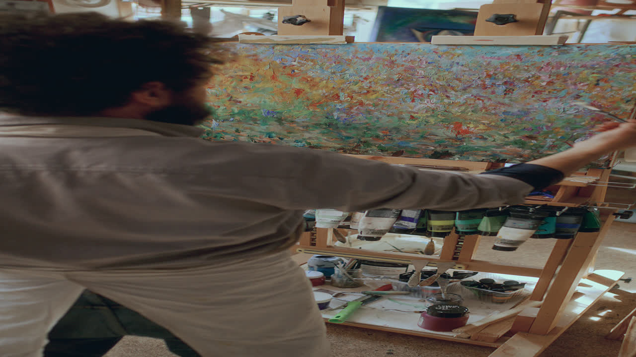 Artist Painting Abstract Picture on Canvas Propped Up on Easel in Studio