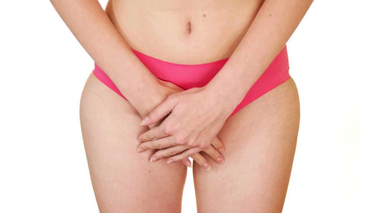 la mujer en ropa interior rosa cubre sus lugares íntimos con las manos y se acurruca con dolor - síndrome premenstrual