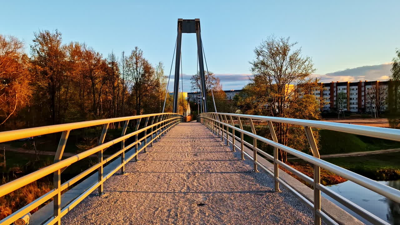 Suspended pedestrian bridge in Valmiera, Latvia with golden light of evening