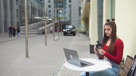mujer joven estudiando al aire libre con portátil y teléfono inteligente