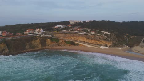 Aerial-view-approaching-the-Praia-do-Magoito-beach,-hazy-sunset-in-Portugal