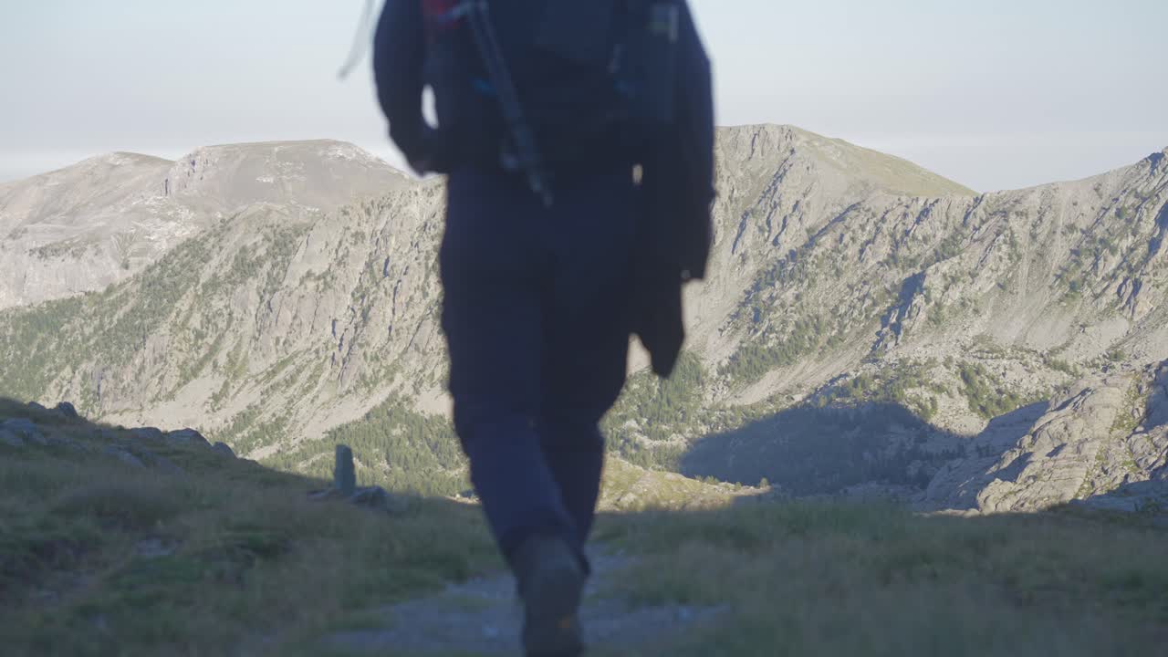 un uomo che fa trekking da solo in montagna, allontanandosi dalla telecamera