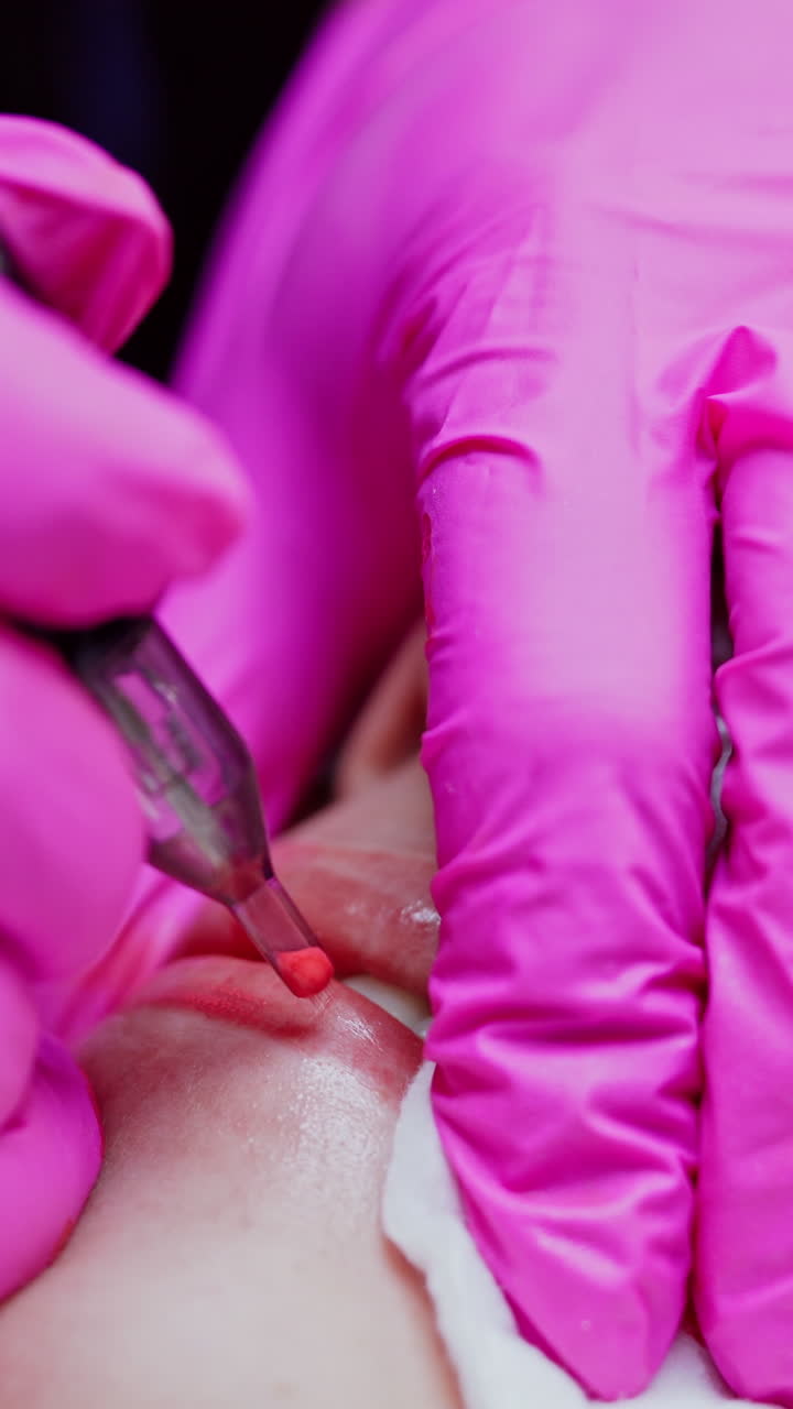 Modern cosmetology in beauty spa. Woman patient receives permanent make-up tattoo on lips in spa salon. Tattooist doing pigmentation of lips. Close-up. Vertical video
