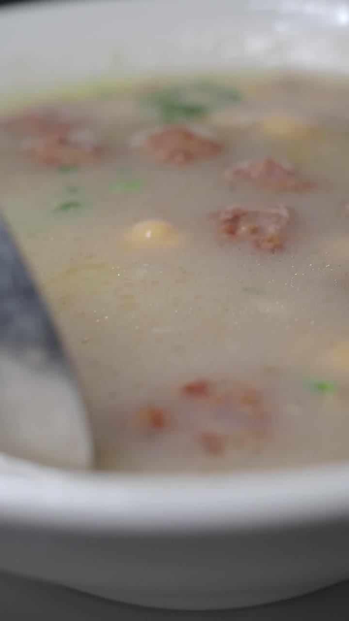 Close-up sendok menyendok sup krim dengan kacang arab dan bakso