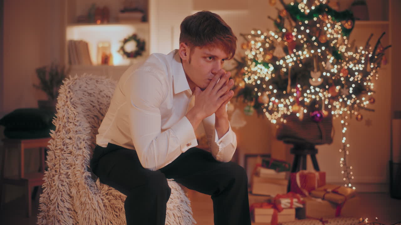 크리스마스 때 집에서 의자에 앉아 손을 고 있는 사려 깊은 남자