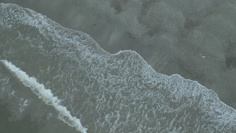 Overhead-rising-aerial-view-of-Ireland's-coastal-beaches-with-waves-rolling-in