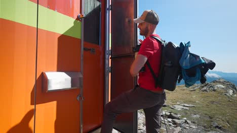 cámara lenta de un fotógrafo masculino abriendo la puerta de la cabaña de la montaña naranja