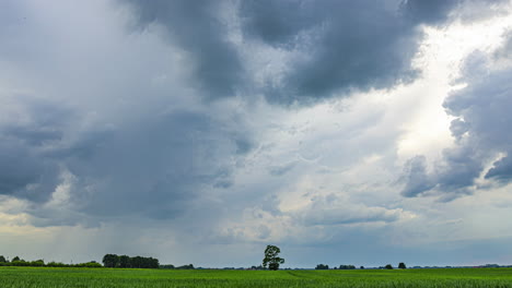 Time-lapse-big-grey-clouds-moving-fast-in-the-sky,-green-field,-grass-pitch