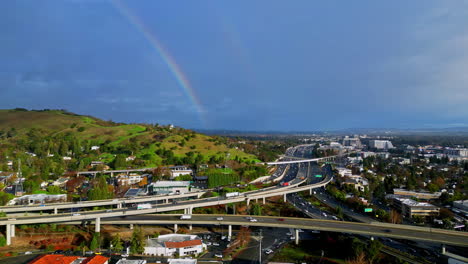 Imágenes-Aéreas-Panorámicas-De-Una-Complicada-Intersección-De-Carreteras,-Un-Arco-Iris-En-El-Cielo