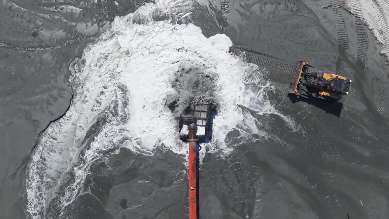 Vista aerea dall'alto di un tubo per il ripascimento della spiaggia che pompa sabbia