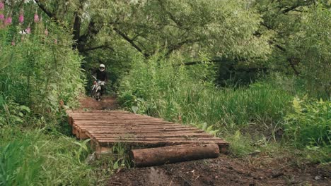 front view of two men riding motocross on a wooden bridge in the forest