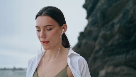 woman walking shore headphones close up. girl listening songs vertical oriented