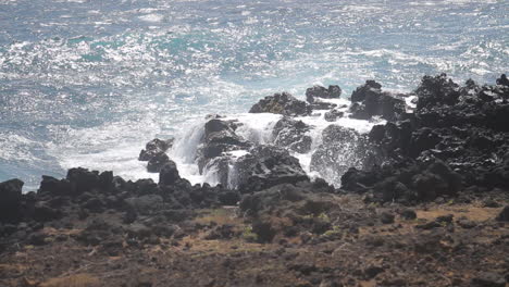 waves crash against shore on black rocks beach in hawaii