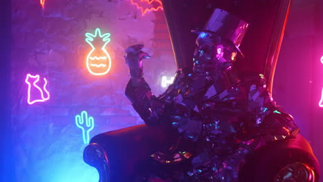 a man in a steel silver metal suit and hat sits in a chair and shakes his head to music in the neon light. she spreads her arms and dances.