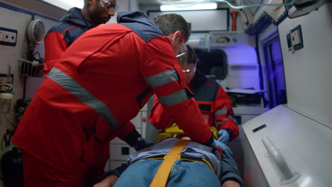 Multiethnic-paramedics-resuscitating-man-in-ambulance-car
