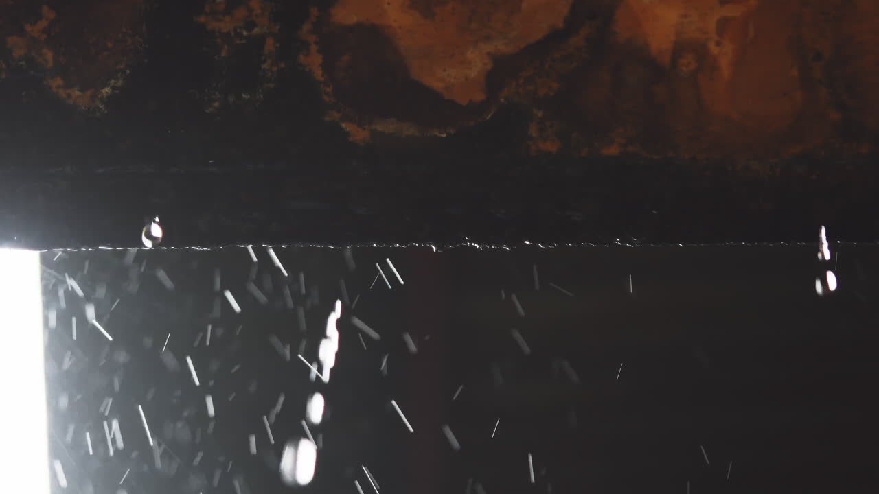 벽의 가장자리에서 떨어지는  ⁇ 물의 강렬한 클로즈업으로 매혹적인 시각적 디스플레이를 만 ⁇ 니다.