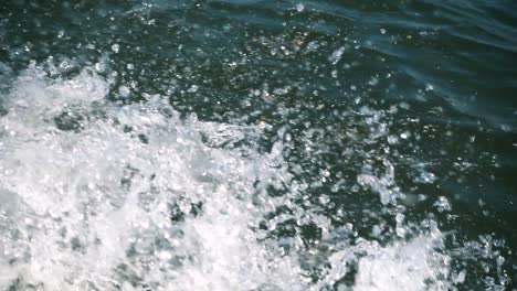 water splashing in slow motion from a boat making its way on a lake