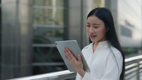 Young Asian Businesswoman on Video Call with Tablet in Urban Setting