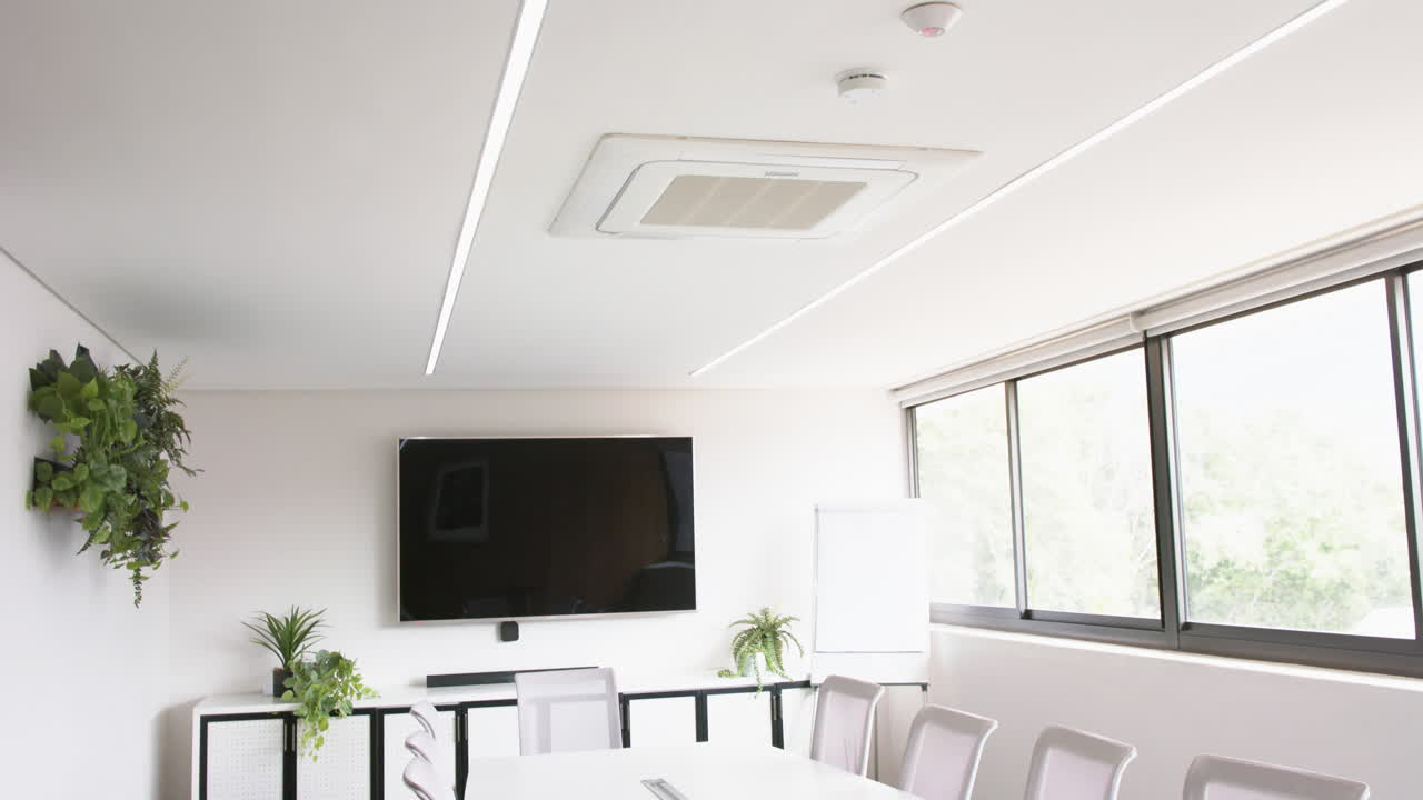 sala de reuniones soleada con mesa, sillas y pantalla en la pared, cámara lenta