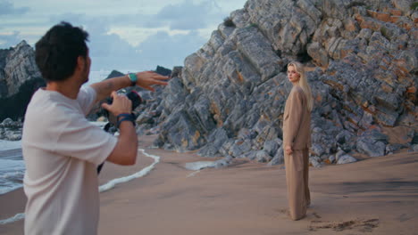 photographer shooting beach girl in suit. blonde model posing at rocky seashore