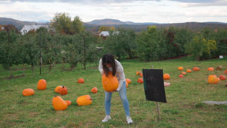 Toma-Escénica-De-Una-Atractiva-Joven-Asiática-Recogiendo-Una-Calabaza-En-Un-Campo