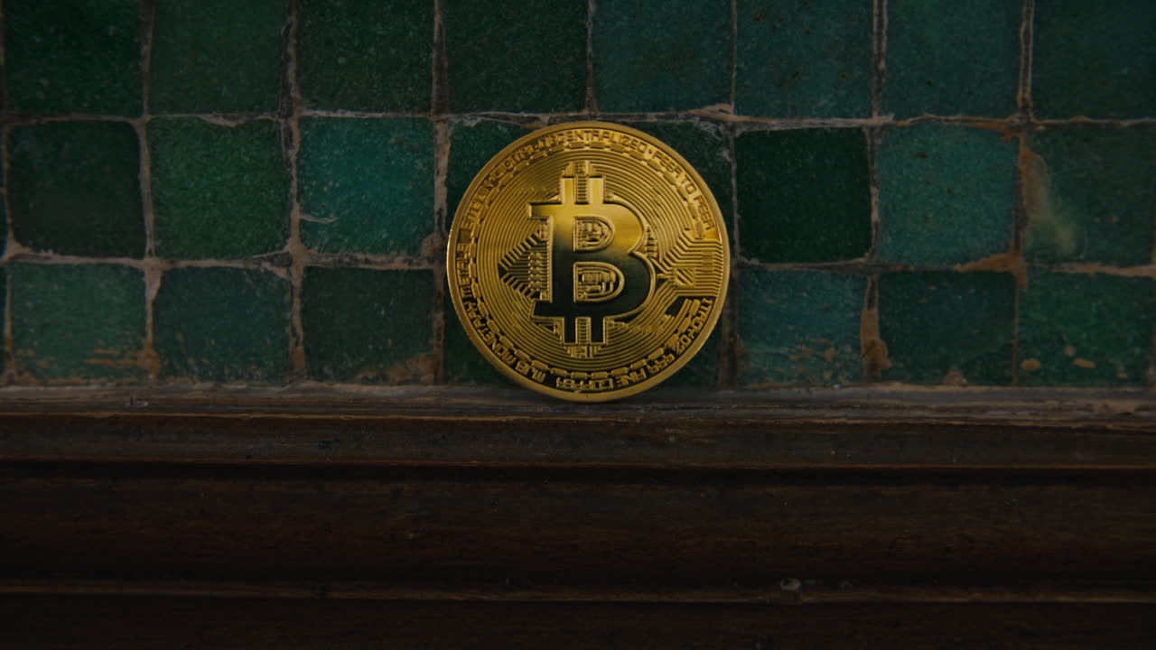 A golden bitcoin shines under soft light as the camera slowly pushes in, highlighting its texture and iconic symbol over aged tiles