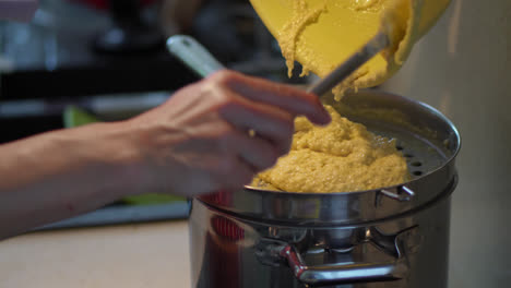 Cocinar-Bryndzove-Halusky---Mujer-Vierta-La-Masa-En-El-Fabricante-De-Spaetzle-Con-Una-Espátula-Y-Empújela-Hacia-El-Agua-Hirviendo