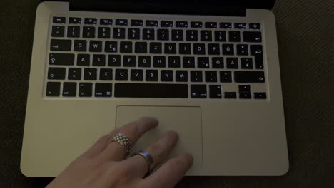 close up top view of male hand with rings sliding and multi touch gestures on macbook