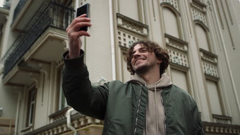 cheerful man speaking on video call outdoor. guy holding cellphone outside.