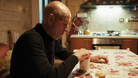 old man relaxing at home eating biscuits with tea