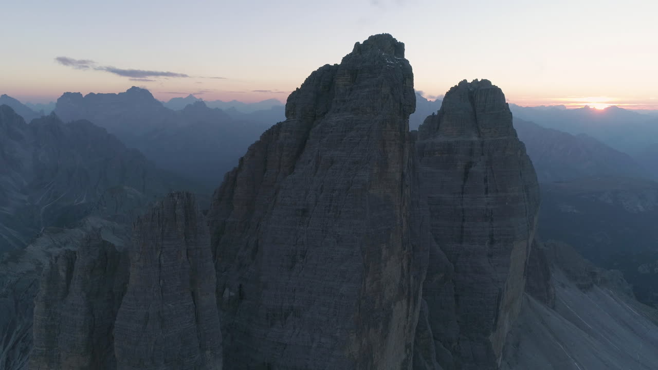 Vista aerea dell'orizzonte nuvoloso e fosco al tramonto, dietro le appuntite vette delle Tre Cime.