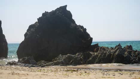 Pequeñas-Olas-Oceánicas-Que-Se-Lavan-Sobre-Una-Formación-Rocosa-Costera-Galesa-Irregular-Con-Neblinosas-Montañas-Snowdonia-En-El-Fondo