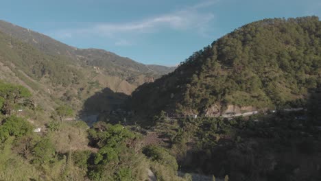 flying-through-valley-close-over-trees-revealing-a-village-in-the-trees-in-a-mountainous-region-of-Philippines-Aerial-reversing-through